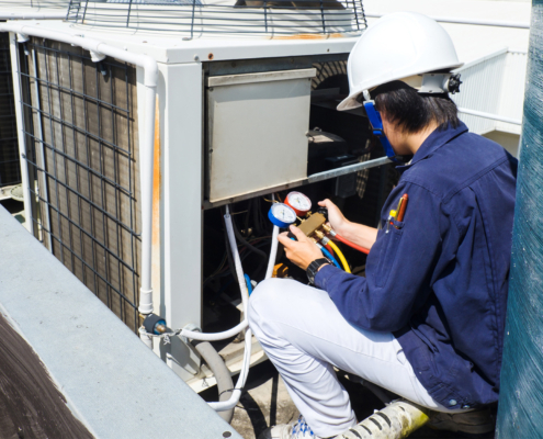 Side view of a technician performing maintenance on a commercial HVAC unit