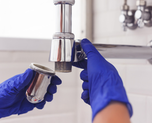 Plumber repairs and maintains chrome siphon under the washbasin
